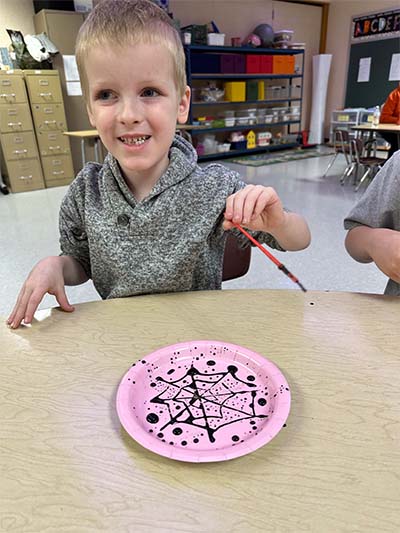 student painting a spiderweb