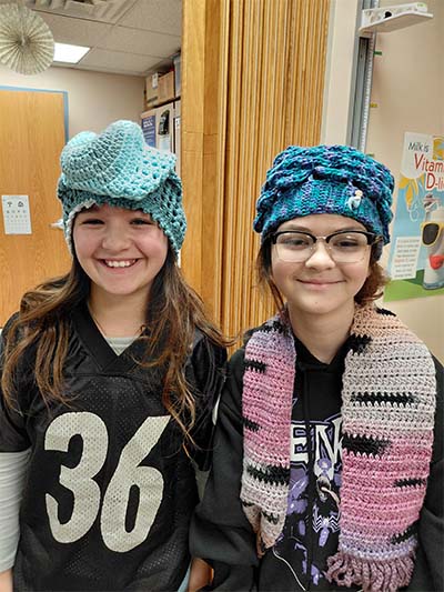 Two students wearing handmade hats