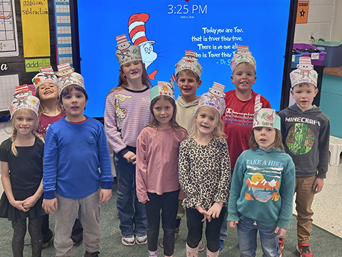 Group of happy elementary students wearing Dr. Seuss hats