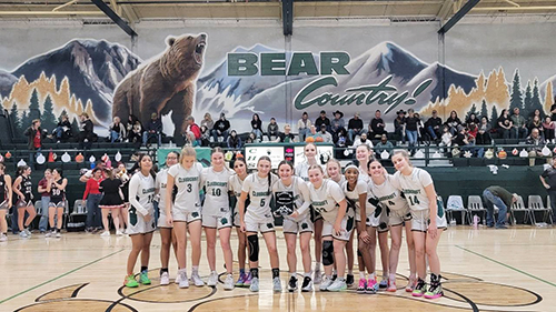 Girls basketball team on the court holding award