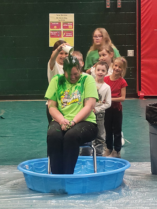 Students having fun pouring slime on a teacher for fun