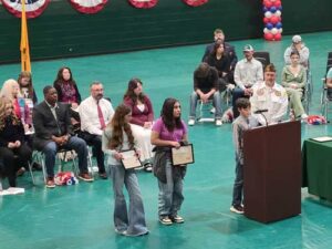Students and adults on stage during a presentation