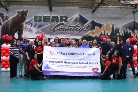 Group of smiling staff holding a Heart Safe School District banner