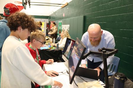 2 male elementary students learning from an adult at a table display