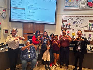 Staff and student making a heart with hands