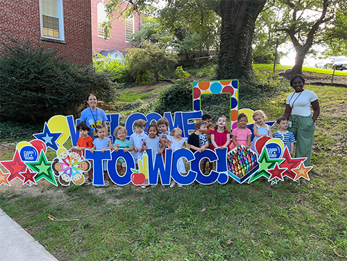 Group of students in a welcome to wcc signs
