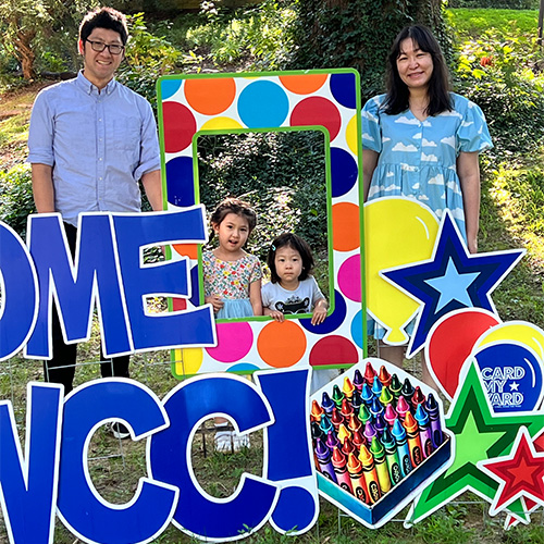 Two students and parents in a welcome to wcc signs