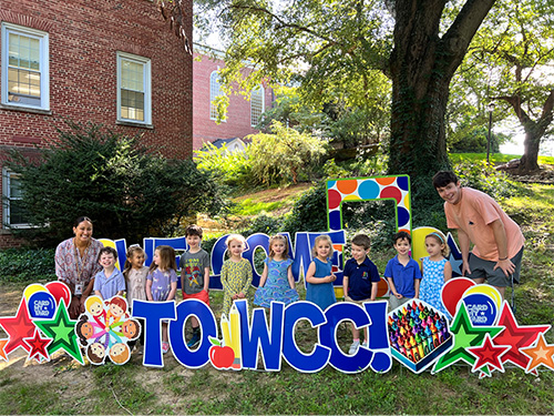 Class of students in a welcome to wcc signs