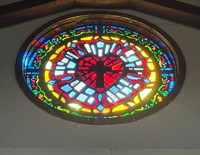 round stained glass window of a cross in a heart