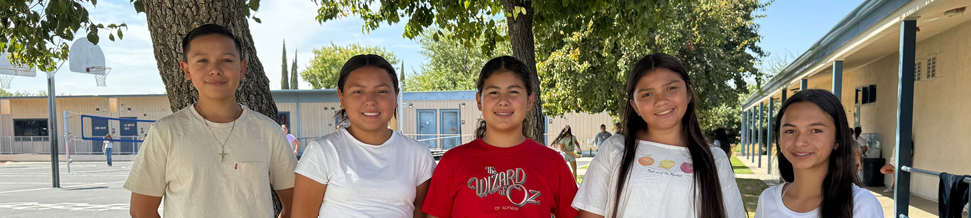 Students smiling outside under a tree