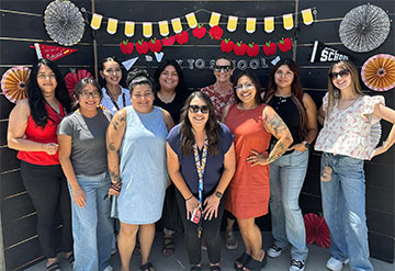 Staff member group photo in front of the first day of school display