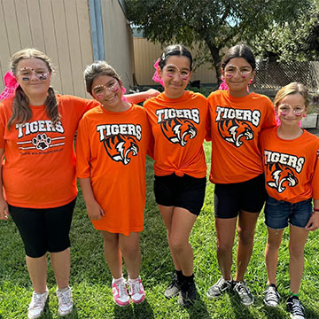 Five students in orange school Tigers logo t-shirts