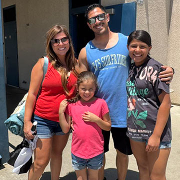 A family smiling in front of the school building A family smiling in front of the school building