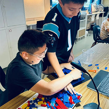 Two students working on a Lego build Two students working on a Lego build