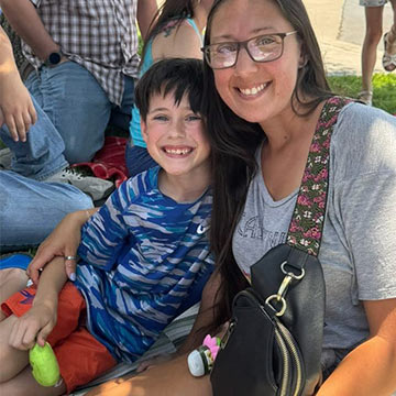 Student and his mom smiling while sitting on the grass Student and his mom smiling while sitting on the grass