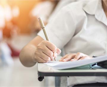 Student writing at a desk