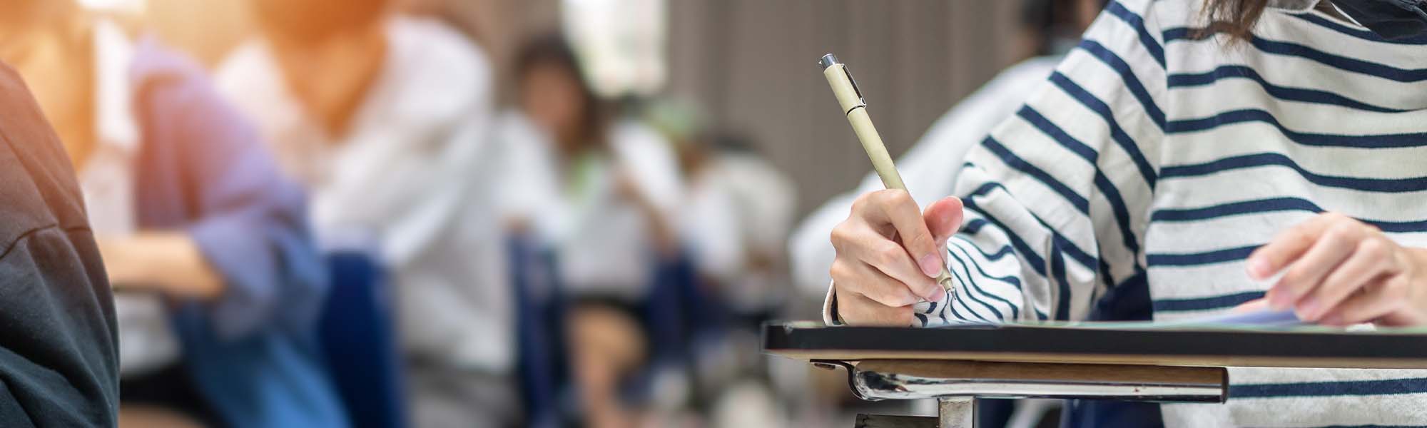 Student writing at a desk