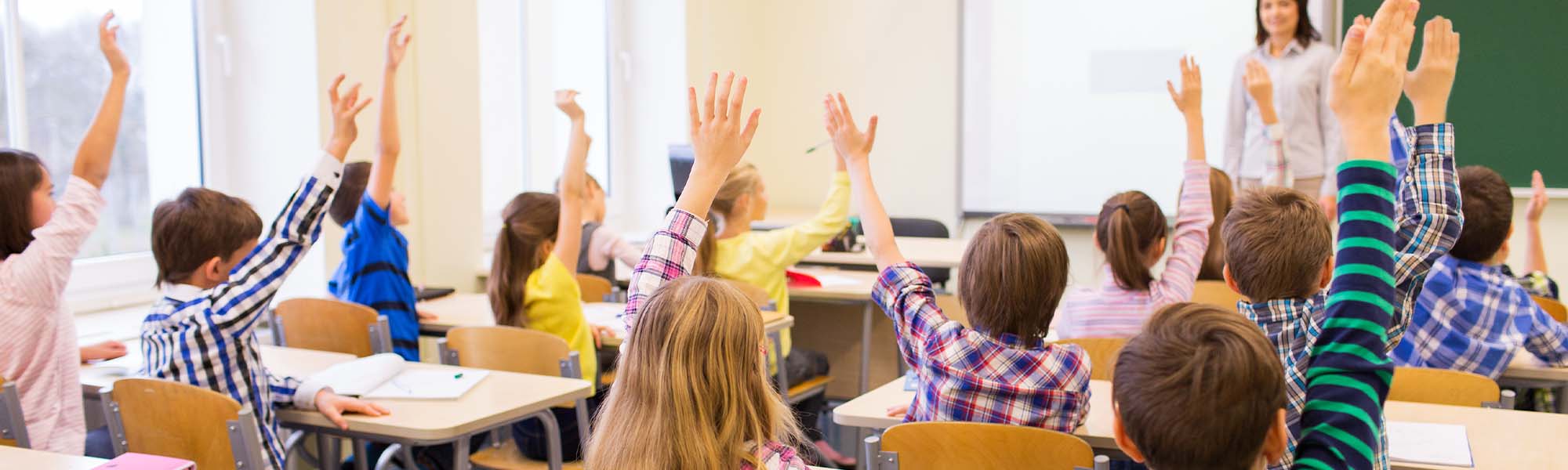 Students raising their hands in their classroom