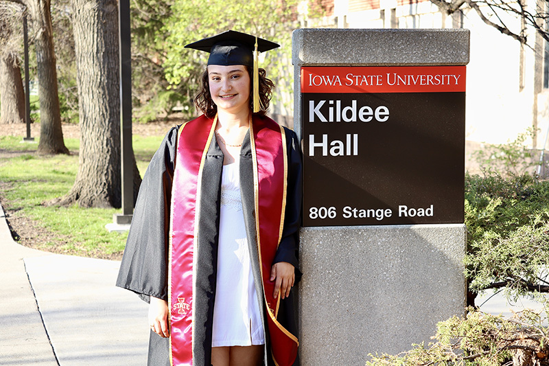 Averi Sievert in graduation attire in front of Iowa State University sign