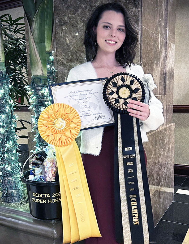 Sophia Metcalf proudly holding up Dressage awards