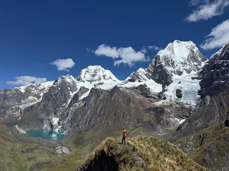 Alex on top of a mountain looking into a valley with a lake