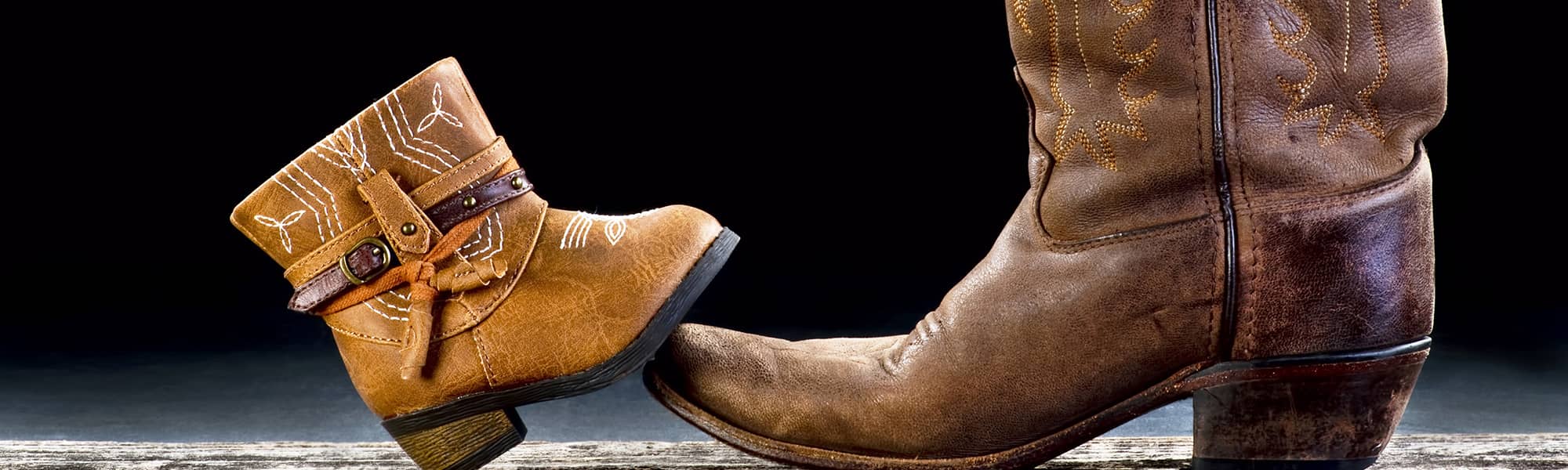 A small cowboy boot leaning on a larger cowboy boot