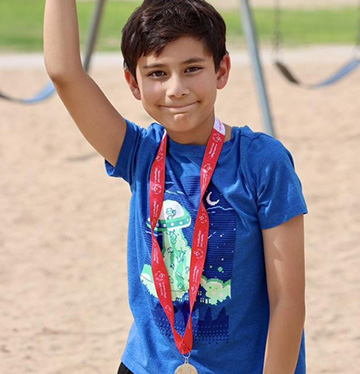 Student smiling at the camera with playground swings in the background
