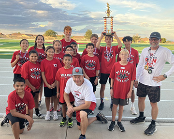 Group picture of the Cross Country Team and Coaches. One is holding up a trophy