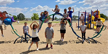 Students posing in front of and on playground equipment