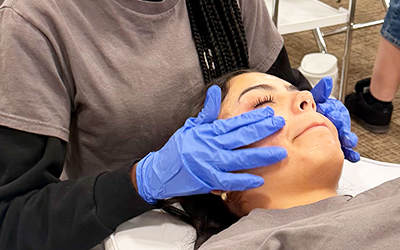 Student tending to a woman client at the Aesthetics Clinic
