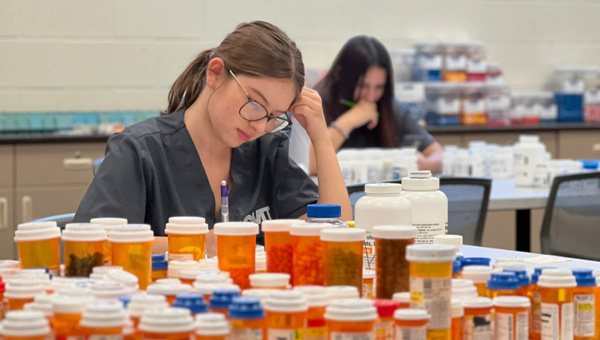students next to a variety of pill bottles