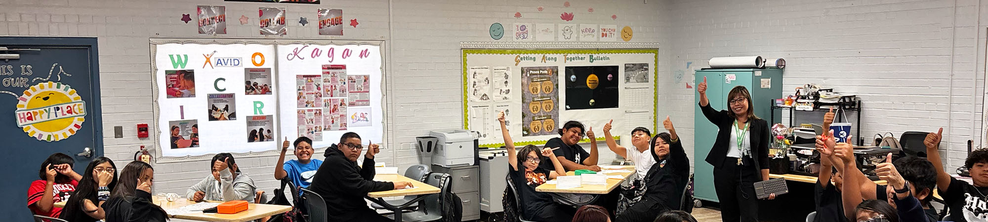 View of a classroom filled with happy students and teacher smiling and waving to the camera