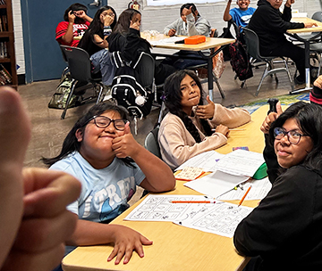 Happy students looking up from their desk to pose for a picture