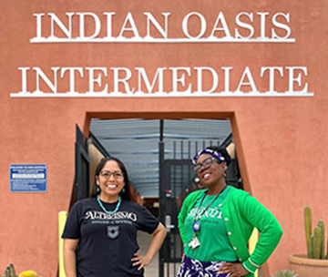 Two staff members in front of school building