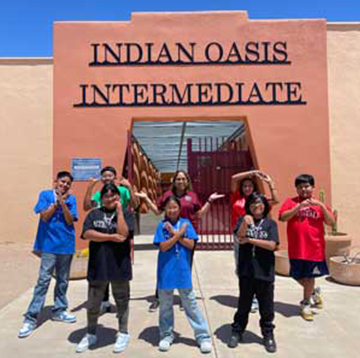 Students outside front of school doing hand signs