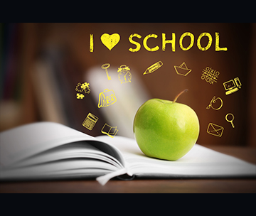 Book with apple on a wooden table with I love school