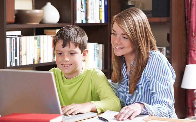 Parent watching son engaged in learning on his laptop