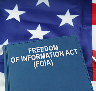 Book that says Freedom of Information Act (FOIA) in front of American flag