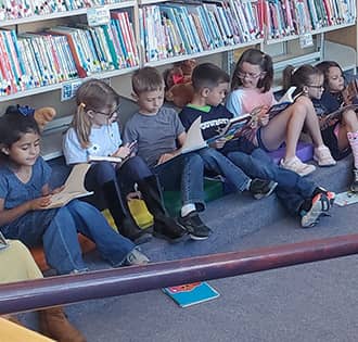 students sitting on library floor reading books