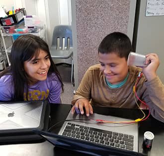 Two middle school girls working on a project outside
