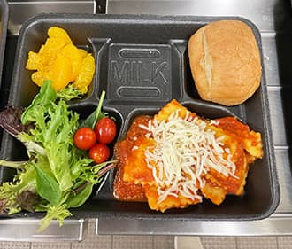 lunch tray with pasta, salad, oranges, and a roll