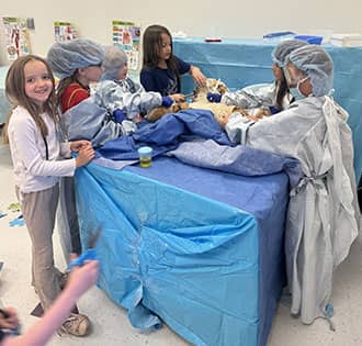 Elementary student learning CPR on a teddy bear