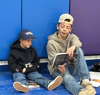 Older student reading to a younger student