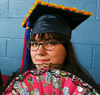 student holding a fan and wearing a graduation cap